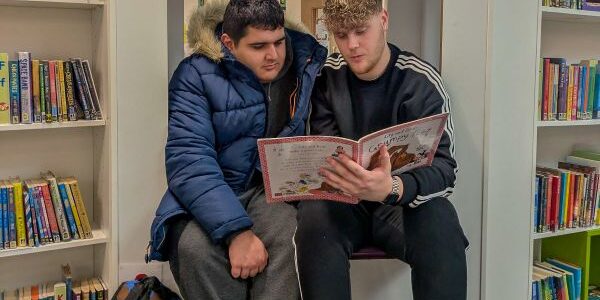 Teens+ Achieves Sector Leading Rating Care Inspectorate Report A Teens+ Project Worker reads a to a Teens+ student from a book in a library